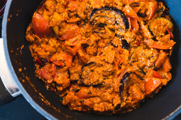 plant-based food, vegan eggplant zucchini and red pepper mix getting sauteed on a pan with mixed spices and red pesto sauce