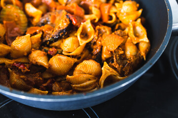 plant-based food, vegan eggplant zucchini and red pepper mix getting sauteed on a pan with mixed spices and red pesto pasta