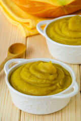 Pumpkin puree in white bowls on a light wooden background