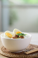Asian food, Rice soup with boiled egg, grilled mushroom and spinach in a bowl on woven rattan sheet