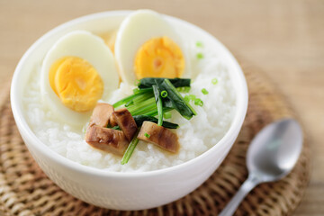 Asian food, Rice soup with boiled egg, grilled mushroom and spinach in a bowl on woven rattan sheet