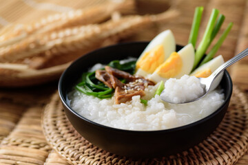 Asian food, Rice soup with boiled egg, grilled mushroom and spinach in a bowl on woven rattan sheet