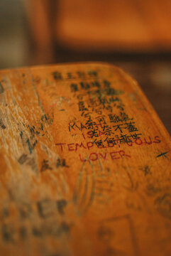 graffiti scratched into school desk top