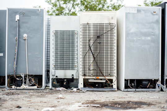 Row of broken refrigerators at a junk yard