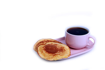 a cup of tea on a saucer and pumpkin pancakes isolated on white background