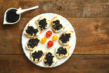 Sandwiches with black caviar on a white plate on the table next to caviar with caviar.