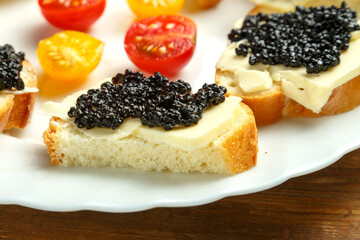 White plate with sandwiches with red caviar on a wooden table.