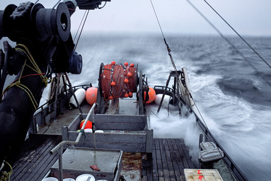 A small boat under steam in open ocean with waves rolling over its deck