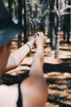 Girl in the forest playing with a tiny homemade sling shot