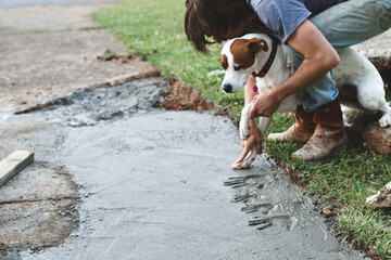 man imprinting dog's paw prints in cement