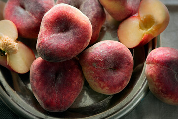 Still life with fresh peaches in a wicker basket on a wooden table.