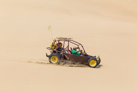Dune buggy with passengers speeding across open ground