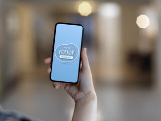 Female hand holding mock up smartphone in blurred background