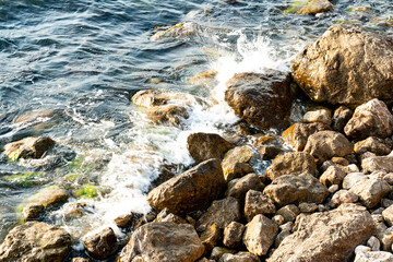 Fototapeta na wymiar The beating of the sea waves against the stones of the rocky coast.