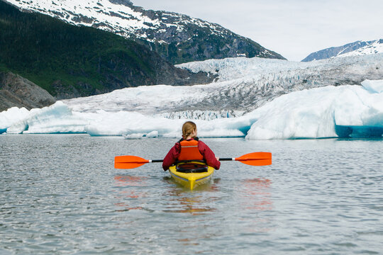 Young woman paddling in a kayak around Mendenhall Glacier