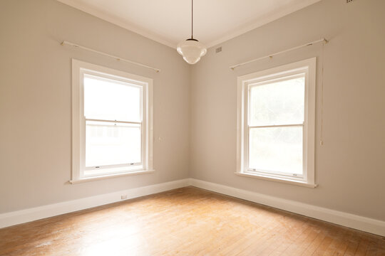empty room with two bright windows and art deco light fitting