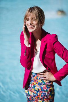 Portrait of a blond girl in a pink suit by the pool in the summer