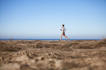 A young woman running along a coastal trail.