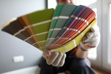 Builder in gloves shows color samples for repair
