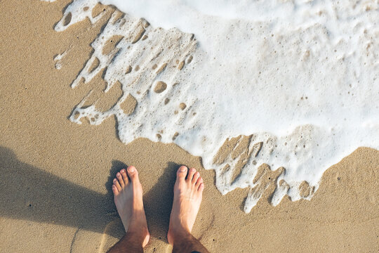 feet at the shores edge on a beach