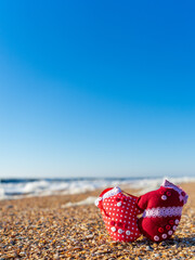 Image of soft toys in the form of mittens on the beach. Handwork.