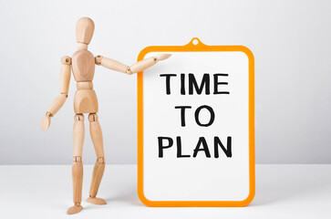 Wooden man shows with a hand to white board with text Time to plan