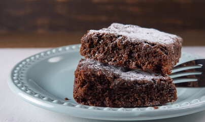 Par de brownies caseros en plato azul con tenedor