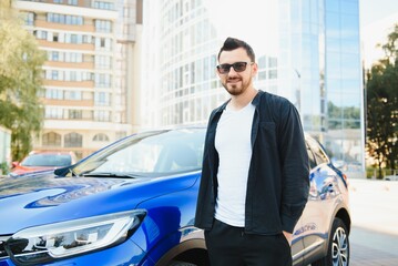 Handsome young man in standing near car outdoors