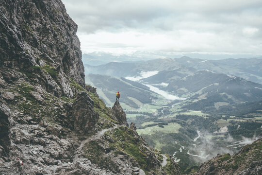 male mountaineer in rugged landscpae standing on a rock overlooking the valley