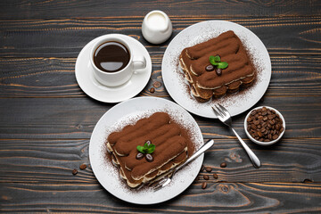 Two portions of Classic tiramisu dessert, cup of coffee and milk or cream on wooden background