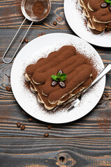 Two portions of Classic tiramisu dessert on ceramic plate on wooden background