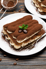 Two portions of Classic tiramisu dessert on ceramic plate on wooden background