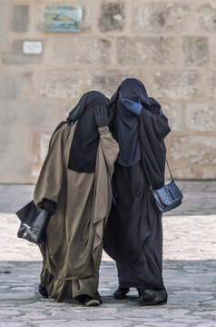 two traditional Muslim women in Medina,North Africa hiding their faces from the camera
