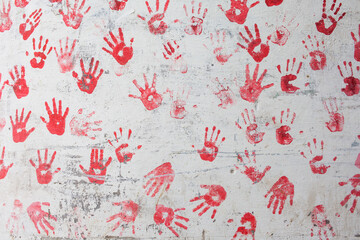 Background of many red palm prints on a white wall.