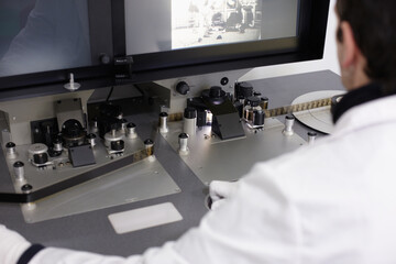 Curator viewing and editing a movie with an old moviola device