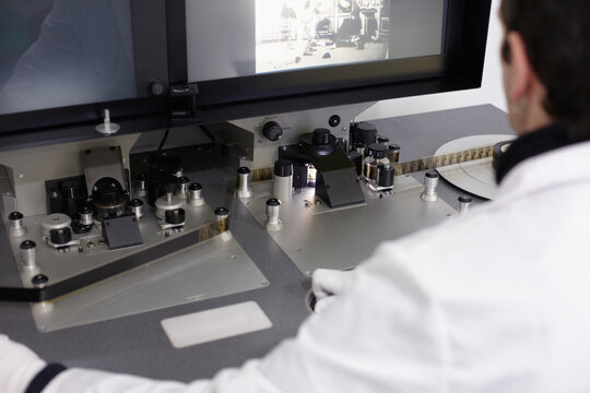 Curator viewing and editing a movie with an old moviola device