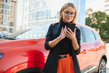 Woman using mobile phone, communication or online application, standing near car on city street or...