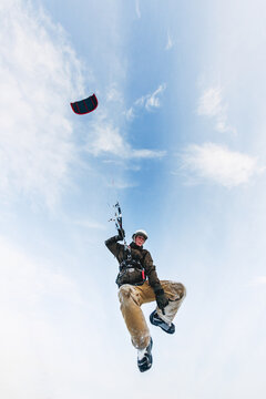 Snow kiter in the air after a jump pointing he does not have his board