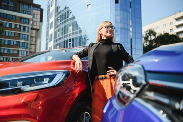 Yong pretty woman standing near a big all terrain car outdoors. Driver girl in casual clothes outside her vehicle.