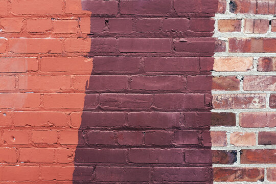 Brown paint covering graffiti on old brick wall