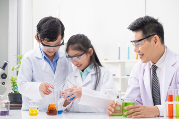 Young Asian boy and girl smile and having fun while learning science experiment in laboratory with teacher in classroom. Study with scientific equipment and tubes. Education concept.