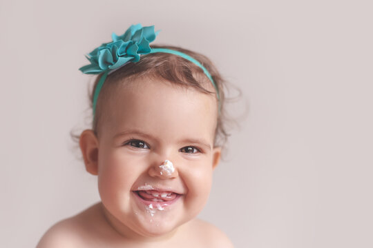 Headshot portrait of a happy, smiling baby with whipped cream on her face