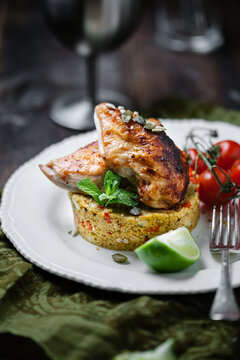 Spicy chicken with couscous on plate in table setting.