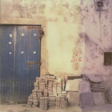 A Blue Door and a Pile of Old Bricks Stacked Next To an Old Moroccan Building