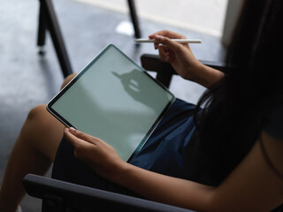 Close-up view of woman using mock up tablet while sitting on a chair