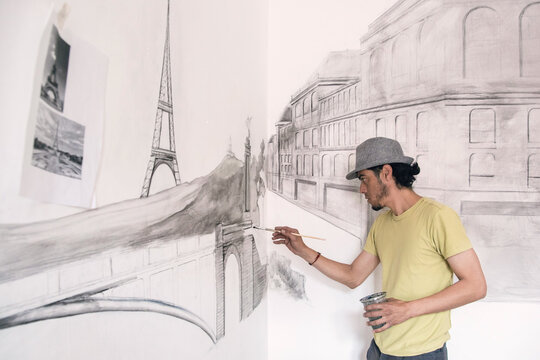 Artist doing a mural painting with scenes from Paris