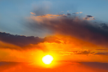 closeup sparkle evening sun among a dense clouds, dramatic sunset background