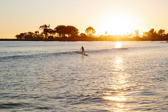 Girl surfer riding a wave during a beautiful sunset