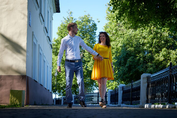 A date between a young girl and a guy on a Sunny summer day. Young beautiful couple on walk in the city. Man and woman at a love meeting with hugs and kisses outdoors