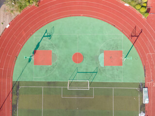 Drone aerial view of the basketball field running track and goal in stadium. Green basketball court and hoop in the sunny day. Quite no people view of sports calm city lift concept Shanghai China